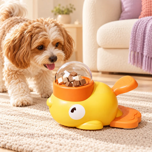 Yellow duck-shaped pet treat dispenser with orange accents and clear reservoir in a supervised pet play scene