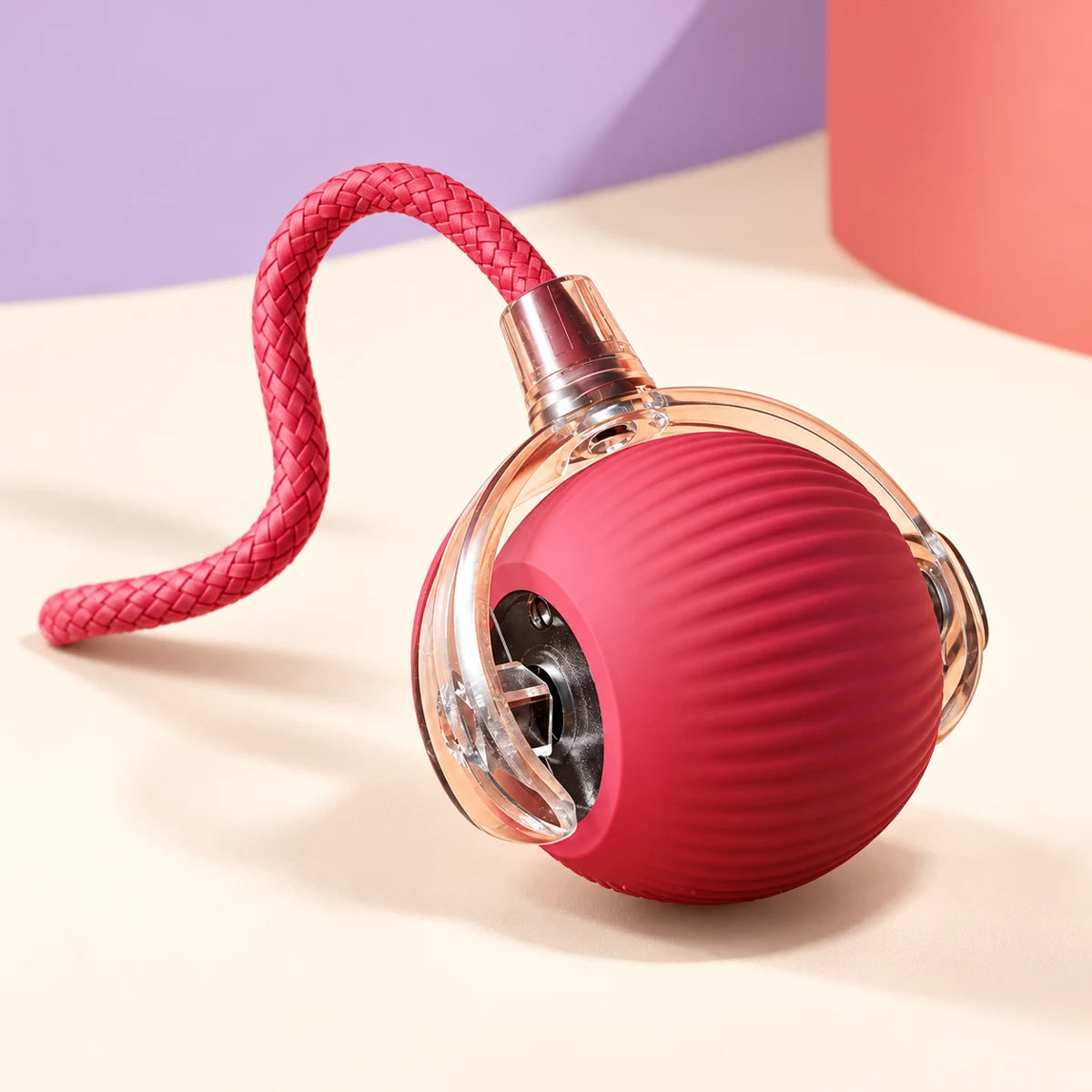 Pink ribbed rolling cat ball in a clear shell with braided pink tail shown from another angle