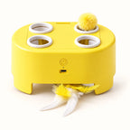 Yellow four-opening cat teaser box with ball and feather attachments on a clean off-white background